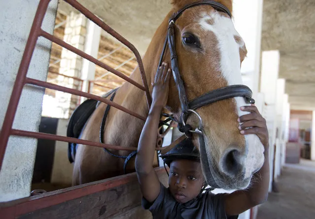 In this January 11, 2017 photo, Judeley Hans Debel, whose right leg is a prosthesis, caresses Tic Tac after riding her at the Chateaublond Equestrian Center in Petion-Ville, Haiti. “You're the best horse, you're the best horse”, the 9-year-old said soothingly to the tan polo pony when he arrived at her stable. (Photo by Dieu Nalio Chery/AP Photo)