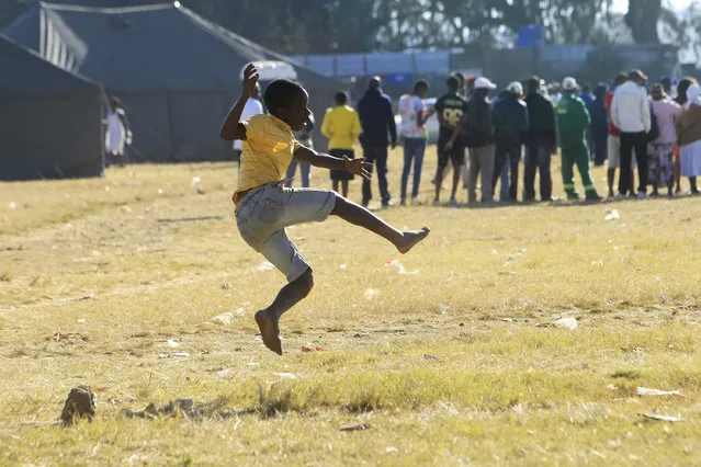 Children play soccer outside a polling station with people queueing to vote in Harare, Zimbabwe, Monday, July 30, 2018. (Photo by Tsvangirayi Mukwazhi/AP Photo)