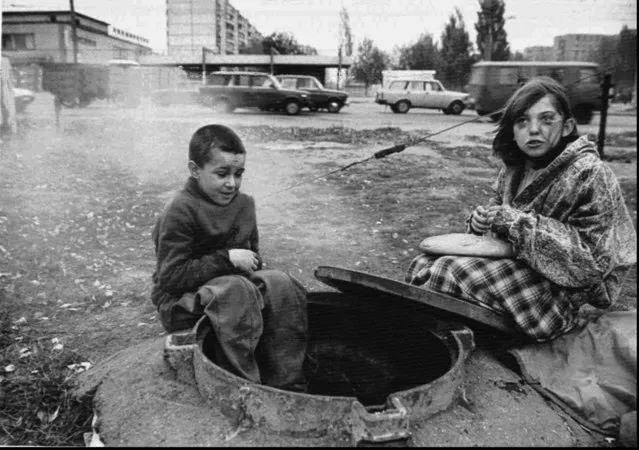 Dima, 9, left, and his sister Oksana, 13, sit near a sewer where they spend nights, in Kharkov, Ukraine, Friday October 20, 1995. The children's father is in a prison and their mother is an alcoholic who is unable to care for them. The children spend the day in the city's railway station and sleep in the sewer because it provides a shelter from cold weather. Most of the social programs in the Ukraine have been severely cut back by the Ukrainian government because of an economic crisis in the country. (Photo by Sergey Dolzhenko/AP Photo)
