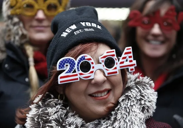 Carmen Glavan, of Monterrey, Mexico, wears 2014 glasses with an American theme as she and others wait in Times Square for the midnight ball drop on New Year's Eve, Tuesday, December 31, 2013, in New York. The crowds will have to wait more than ten hours for the ball drop. (Photo by Kathy Willens/AP Photo)