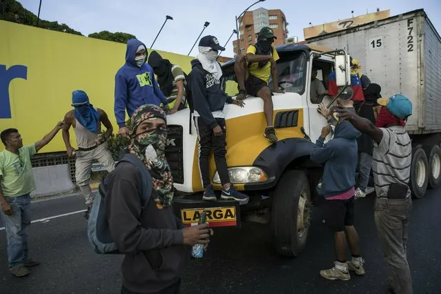 Anti-government protesters stop a truck while blocking a highway with a small group of demonstrators who were returning from a peaceful demonstration called by self-declared interim president Juan Guaido to demand the resignation of President Nicolas Maduro, in Caracas, Venezuela, Saturday, February 2, 2019. (Photo by Rodrigo Abd/AP Photo)