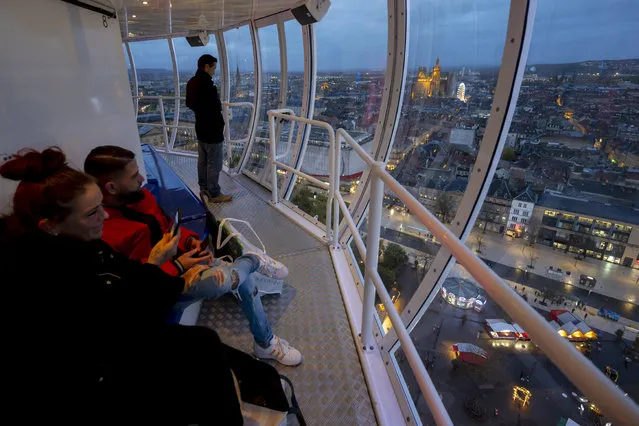 Visitors look on from inside The City Skyliner, one of the highest mobile observation towers in the world, in Metz, northeastern France, on November 22, 2022. The City Skyliner, one of the highest mobile observation tower of the world, is installed in France for the first time, in Metz, northeastern France, amid the Christmas Market, with a total height of 81 metres, a lift height of 72 metres and a capacity of 60 people. (Photo by Jean-Christophe Verhaegen/AFP Photo)