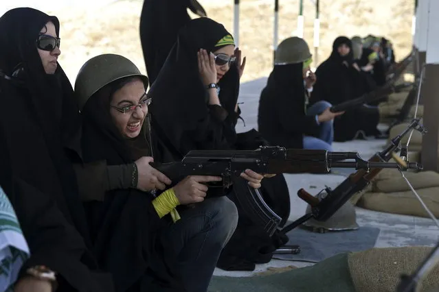 In this Thursday, August 22, 2013 photo, a female member of the Basij paramilitary militia aims her rifle as a trainer assists her during a training session in Tehran, Iran. (Photo by Ebrahim Noroozi/AP Photo)