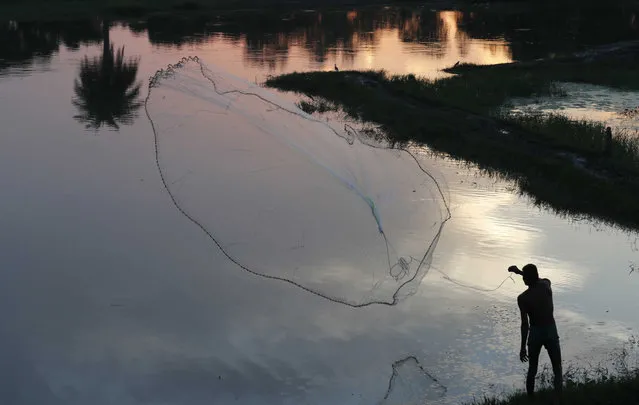 A man throws his net for fishing in a pond in Sitapur, Uttar Pradesh state, India, Monday, September 27, 2021. (Photo by Rajesh Kumar Singh/AP Photo)