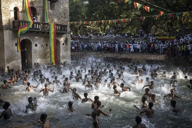 Ethiopian Orthodox worshippers bath in the Fasilides Bath during the celebration of Timkat, the Ethiopian Orthodox Epiphany, in Gondar on January 20, 2024. Timkat is the Ethiopian Orthodox Christian festival which celebrates the baptism of Jesus in the Jordan river. A sense of dullness marred the celebrations this year due to unrest and clashes plaguing the wider Amhara region - and the city of Gondar in particular, failing to attract the usual multitude of worshippers that flock at the UNESCO World Heritage Site. The conflict in the region sees the Ethiopian National Defense Force battling an ethnic Amhara militia known as “Fano”. Although these fighters fought alongside federal troops in the past, tensions boiled over after Addis Ababa announced in April 2023 that it was dismantling all regional armed forces across Ethiopia. (Photo by Michele Spatari/AFP Photo)