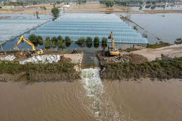 This aerial photo taken on October 11, 2021 shows rescuers digging a spillway with an excavator to release flood waters after heavy rainfall at a flooded area in Jiexiu in the city of Jinzhong in China's northern Shanxi province on October 11, 2021. (Photo by AFP Photo/China Stringer Network)