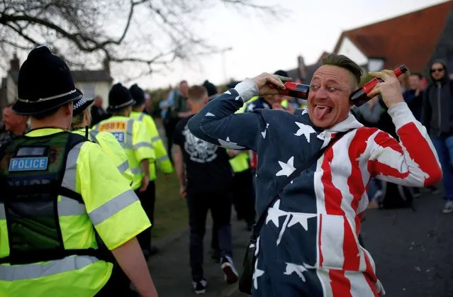A fan gestures next to a police officer while celebrating the life of British singer Keith Flint of techno group The Prodigy after his funeral in Braintree, Essex, Britain, March 29, 2019. (Photo by Henry Nicholls/Reuters)