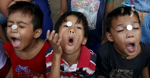 Boys take part in a coin game contest during a celebration of religious patron Nuestro Senor Jesucristo in Quezon city, Philippines May 3, 2015. The winner of the contest is the one who gets the coin inside the mouth first without touching the coin. (Photo by Erik De Castro/Reuters)