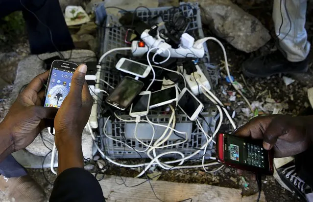 Sudanese immigrants charge their mobile phones at a make-shift electric outlet in the western Greek town of Patras May 4, 2015. (Photo by Yannis Behrakis/Reuters)