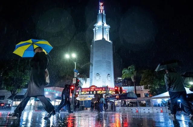 People walk in the rain past the Fox Theater before the premier of Bob Marley: One Love Tuesday, February 6, 2024, in the Westwood area of Los Angeles. (Photo by Ethan Swope/AP Photo)