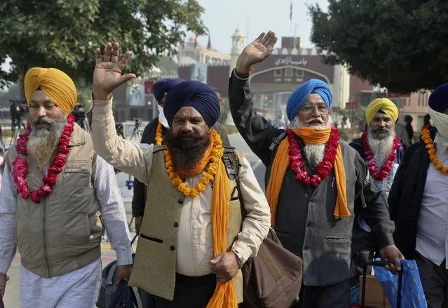 Indian Sikh pilgrims wave to journalists while entering Pakistan through the Wagah border crossing point, near Lahore, Pakistan, Wednesday, November 17, 2021. Hundreds of Indian Sikh pilgrims arrived in Pakistan to participate in a festival to celebrate the 552nd birth anniversary of their spiritual leader Baba Guru Nanak, the founder of Sikh religion, at Nankana Sahib near Lahore. (Photo by K.M. Chaudary/AP Photo)
