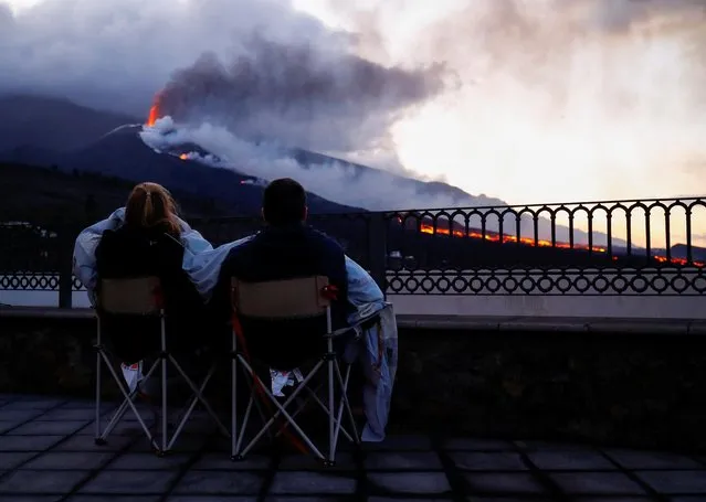 Two tourists watch how the Cumbre Vieja volcano continues to expel lava as seen from the Tajuya viewpoint on the Canary Island of La Palma, Spain, November 27, 2021. (Photo by Borja Suarez/Reuters)