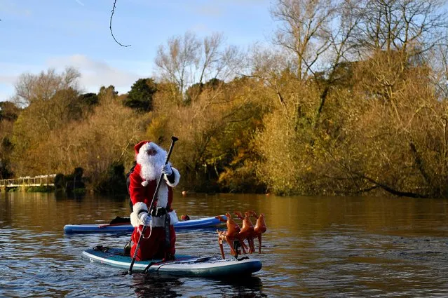 A paddle boarder dressed as Santa Claus paddles down the River Liffey to bring Christmas cheer against the coronavirus disease (COVID-19) gloom, in the city centre of Dublin, Ireland, December 5, 2021. (Photo by Clodagh Kilcoyne/Reuters)