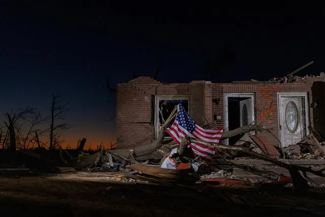 A U.S. flag is tied to a fallen tree in front of a destroyed residence in the aftermath of a tornado in Mayfield, Kentucky, U.S., December 13, 2021. (Photo by Adrees Latif/Reuters)