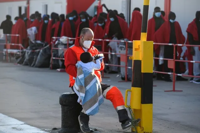 A Red Cross member feeds a baby with a bottle at Gran Carajal port after the arrival of some migrants on board a Spanish Sea Rescue Unit's ship in Gran Canaria island, southwestern Spain, 31 January 2023. Spanish authorities rescued some 171 migrant, including 14 women and four children, on board of three boats last night off southern Canary Islands coast. (Photo by Carlos de Saa/EPA/EFE)