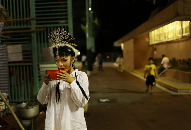 A Chinese opera actress drinks a bowl of soup before her performance at a makeshift theater during the “Hungry Ghost Festival” in Hong Kong, Tuesday August 20, 2013. The Hungry Ghost Festival is celebrated during the seventh month in the Chinese lunar calendar.  (Photo by Vincent Yu/AP Photo)