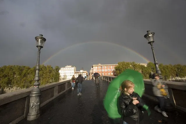 A girl plays with an umbrella as a rainbow appears in background, in Rome, Thursday, November 10, 2016. (Photo by Alessandra Tarantino/AP Photo)
