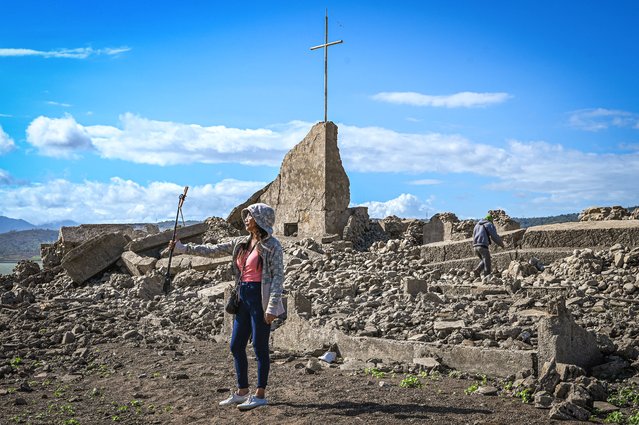 A woman takes a photo near the ruins of a church at the old sunken town of Pantabangan in Nueva Ecija province on April 26, 2024. (Photo by Jam Sta Rosa/AFP Photo)