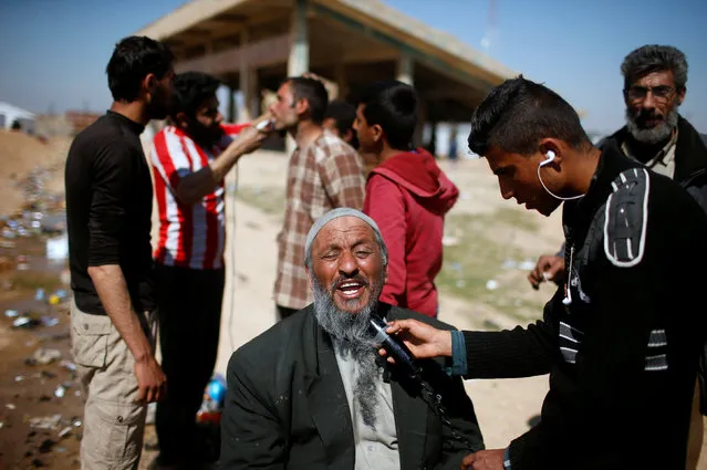 One of the displaced Iraqis who flee their homes has his beard shaved outside Hamam al-Alil camp, south of  Mosul, Iraq March 10, 2017. (Photo by Suhaib Salem/Reuters)