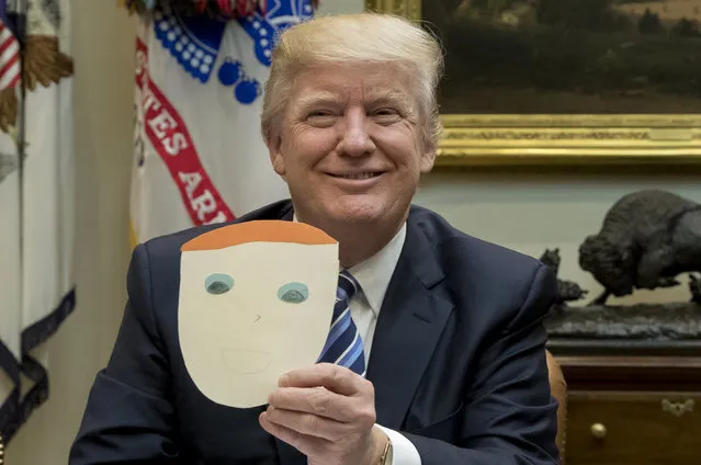 President Donald Trump holds up a note and drawing depicting him that was created by the child of Greg Knox of Ohio, during a meeting on healthcare in the Roosevelt Room of the White House on March 13, 2017 in Washington, DC. The House Republicans' bill known as the “American Health Care Act”, which is intended to replace the Affordable Care Act and is endorsed by President Trump, has faced criticism from both Republicans and Democrats. (Photo by Michael Reynolds/Pool/Getty Images)