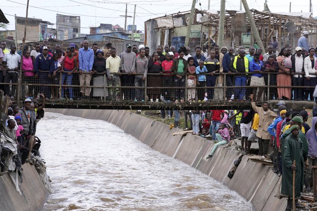 People stand on a bridge, as they watch houses in riparian land being demolished in the Mukuru area of Nairobi, Tuesday, May. 7, 2024. The government ordered the demolition of structures and buildings, illegally constructed along riparian areas. Kenya, along with other parts of East Africa, has been overwhelmed by flooding. (Photo by Brian Inganga/AP Photo)