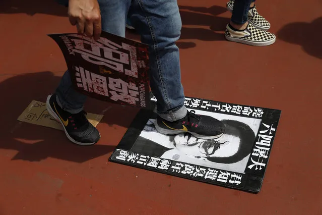 A protester steps on a poster depicting former Chinese Premier Li Peng with the words "June 4th Butcher" who recently passed away, during a rally In Hong Kong Saturday, July 27, 2019. Thousands of protesters began marching Saturday despite police warnings that their presence would spark confrontations with local residents. Demonstrators wearing black streamed through Yuen Long, the area where a mob brutally attacked people in a commuter rail station last Sunday. (Photo by Vincent Yu/AP Photo)