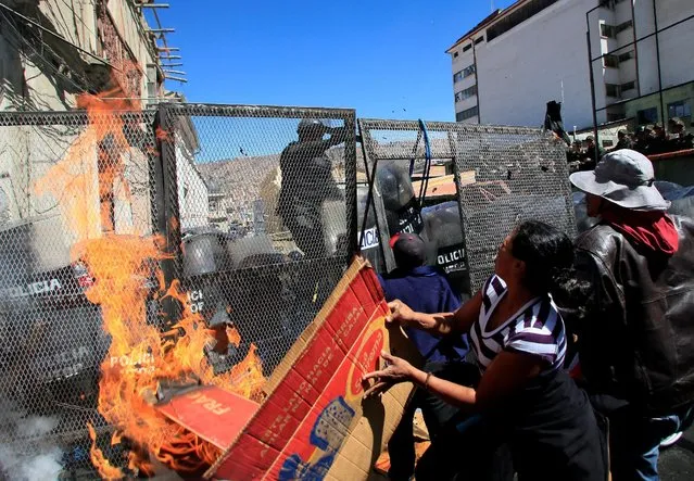 Demonstrators try to set fire to a police barricade, during a protest by people with physical disabilities demanding the government to increase their monthly disability subsidy, in La Paz, Bolivia, April 29, 2016. (Photo by David Mercado/Reuters)