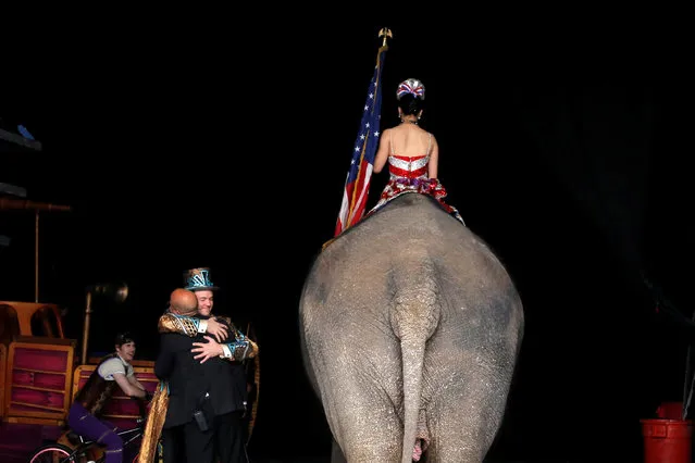 Ringmaster David Shipman embraces Senior Elephant Handler Ryan Henning as a performing elephant prepares to enter the arena in Ringling Bros and Barnum & Bailey Circus' “Circus Extreme” show at the Mohegan Sun Arena at Casey Plaza in Wilkes-Barre, Pennsylvania, U.S., April 30, 2016. (Photo by Andrew Kelly/Reuters)