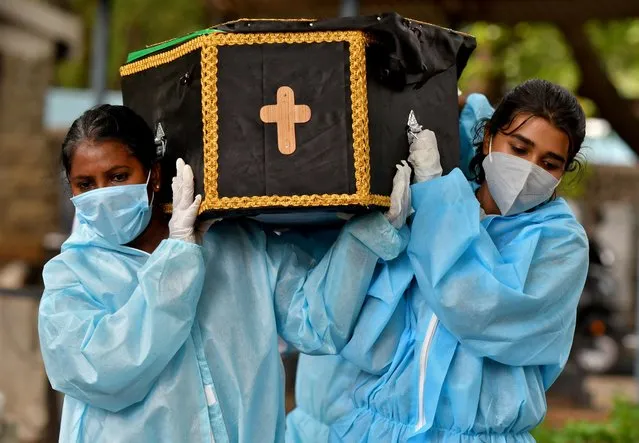 Volunteers Akshaya (R), 22, a law student, and Esther Mary, 41, a lecturer, carry the body of a person who died from COVID-19 for burial at a cemetery in Bengaluru, India, May 18, 2021. Citizen volunteers risk their own personal safety to help families affected by the country's devastating second wave, saying they been moved to act by desperate pleas for help on social media and in their local communities. (Photo by Samuel Rajkumar/Reuters)