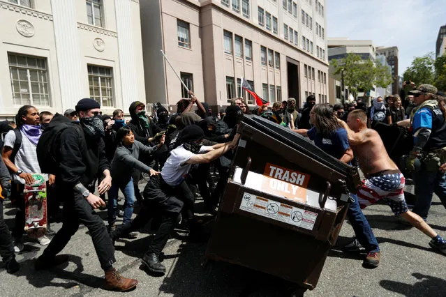 Demonstrators for (R) and against (L) U.S. President Donald Trump push a garbage container toward each other during a rally in Berkeley, California in Berkeley, California, U.S., April 15, 2017. (Photo by Stephen Lam/Reuters)