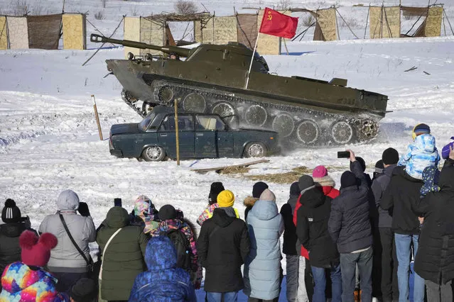 People look at a tank crushing a car during a military show at a military park in St. Petersburg, Russia, Sunday, March 6, 2022. (Photo by AP Photo/Stringer)