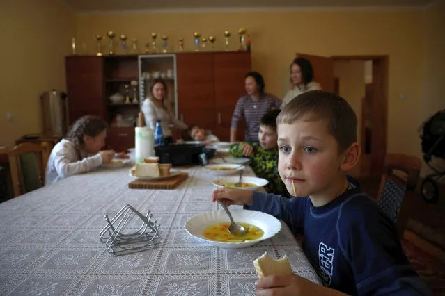 Ukrainian boy Vladislaw, 7, who fled Russia's invasion of Ukraine eats at a living room of a clergy house in Lubaczow, Poland March 21, 2022. Polish Catholic priest Roman Karpowicz hosts women with children from Ukraine who fled the invasion at the clergy house. (Photo by Kacper Pempel/Reuters)