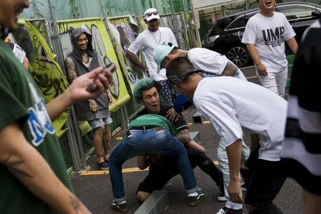 Crew and cast members tussle in jest during a break in a music video shoot in the trendy Harajuku district in Tokyo, July 17, 2015. (Photo by Thomas Peter/Reuters)