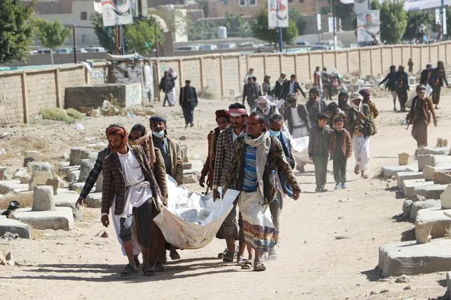 Relatives carry bodies of the victims of air strikes on a detention center to be buried at a cemetery in Saada, Yemen on January 25, 2022. (Photo by Naif Rahma/Reuters)
