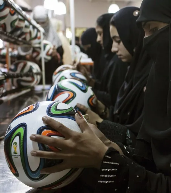 Employees conduct a final check to fix any cavities in the seams of balls inside the soccer ball factory that produces official match balls for the 2014 World Cup in Brazil, in Sialkot, Punjab province May 16, 2014. (Photo by Sara Farid/Reuters)