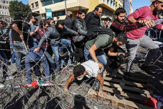 Lebanese protesters flee from security forces on their way back after having cut through the security barrier leading to the government palace at Riad al-Solh square in the capital Beirut's downtown district on November 19, 2019. An unprecedented protest movement against the ruling elite entered its second month with the country in the grip of political and economic turmoil. The leaderless pan-sectarian movement has swept the Mediterranean country since October 17, prompting the resignation of Prime Minister Saad Hariri's government. (Photo by Anwar Amro/AFP Photo)