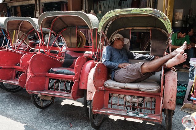 The driver of a bechak, a traditional pedicap, sleeps in front of a market in Surakarta, Central Java, on July 31, 2024. (Photo by Yasuyoshi Chiba/AFP Photo)