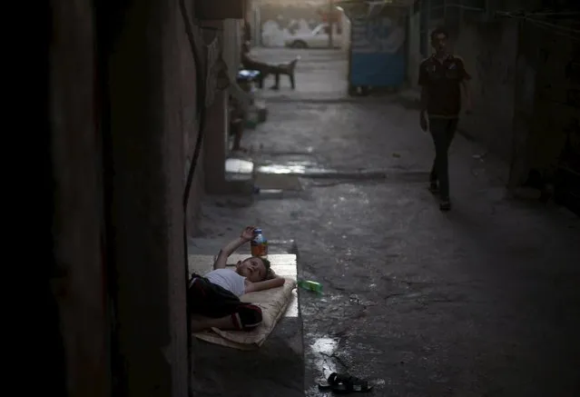 A Palestinian boy lies outside his family house to escape the heat during power cuts at Shatti (beach) refugee camp in Gaza City July 28, 2015. (Photo by Mohammed Salem/Reuters)