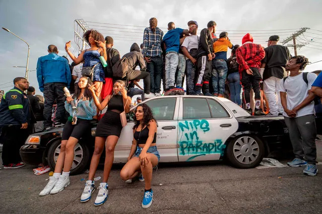 Fans and community members gather around a LAPD car along the procession route for Nipsey Hussle after his memorial at the Staples Center in Los Angeles, California, April 11, 2019. 4 people shot and 1 dead during the procession LAPD reported on late April 11, 2019 The Grammy-nominated artist was killed in front of The Marathon Clothing store he founded in 2017. (Photo by Kyle Grillot/AFP Photo)