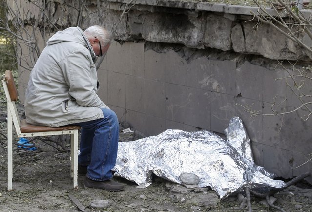 A relative sits next to the covered body of a 9-year-old girl near a health center damaged in a missile strike in Kyiv (Kiev), Ukraine, 01 June 2023, amid the Russian invasion. At least three people died, including a child, and ten others were injured after a missile attack on the Ukrainian capital, the National Police said. Russian troops entered Ukrainian territory in February 2022, starting a conflict that has provoked destruction and a humanitarian crisis. (Photo by Sergey Dolzhenko/EPA/EFE)