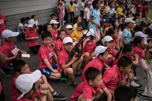 A boy holds a mock rifle as he sits with others to take part in sports games marking “Children's Union Foundation day”, in Pyongyang on June 6, 2017. (Photo by Ed Jones/AFP Photo)