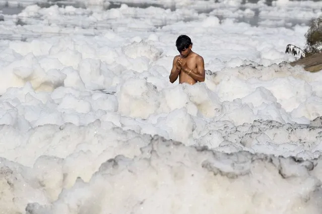 In this photograph taken on July 8, 2017 an Indian Hindu devotee prays amongst foam in the polluted Yamuna river in New Delhi. (Photo by Dominique Faget/AFP Photo)