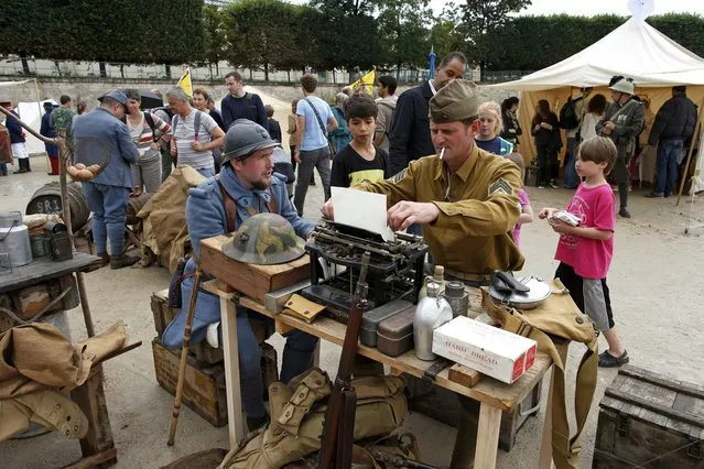 Men dressed in vintage American and French World War I military uniforms take part in a military camp reconstitution in the Tuileries Garden in Paris on the eve of Bastille Day, on Jule 14, 2014. (Photo by Benoit Tessier/Reuters)