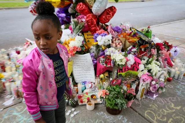 A young girl looks at a memorial in the wake of a weekend shooting at a Tops supermarket in Buffalo, New York, U.S. May 18, 2022. (Photo by Brendan McDermid/Reuters)