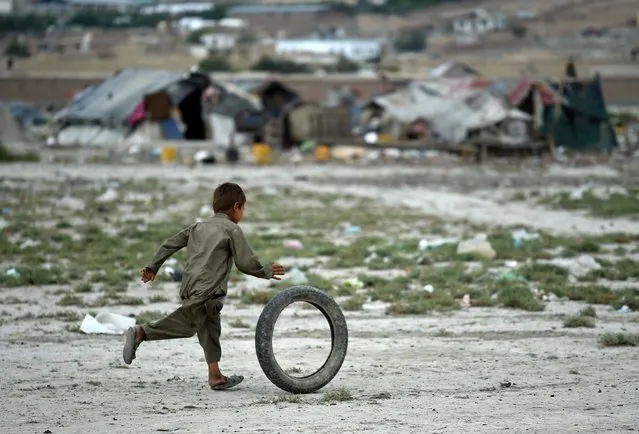 An Afghan Kochi nomad boy plays with a tire outside his tent on the outskirts of Kabul on August 2, 2015. (Photo by Wakil Kohsar/AFP Photo)