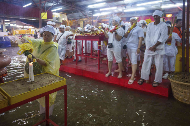 Ethnic Chinese devotees pray at a flooded temple during the eve of Nine Emperor Gods festival in Kuala Lumpur, Malaysia, Wednesday, October 2, 2024. White-clad worshippers lit candles and offered sacrifices to their deities. The nine-day festival has been practiced for many generations by ethnic Chinese in this country. (Photo by Vincent Thian/AP Photo)