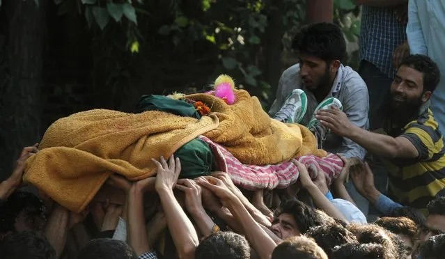 A Kashmiri villager stretches out to touch the body of Manzoor Ahmad, a suspected militant commander, being carried for his funeral at Pulwama, about 49 kilometres (31 miles) south of Srinagar, India, Thursday, June 30, 2016. Indian forces killed two suspected rebels in a clash Thursday in Indian-controlled Kashmir, and dispersed hundreds of protesters who took to the streets to show their solidarity with the rebels, an official said. (Photo by Mukhtar Khan/AP Photo)