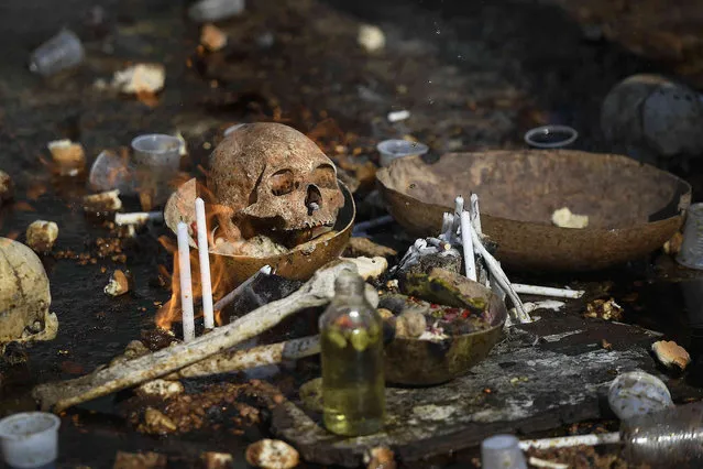 A skull sits on the ground as part of an altar during ceremoies honoring the Haitian Voodoo spirit of Baron Samdi and Gede at the National Cemetery in Port-au-Prince, Haiti, Monday, November 1 2021. Followers of Voodoo join the Fete Gede celebration of the spirits, equivalent to the Roman Catholic festivity of the Day of the Dead and All Saints Day. (Photo by Matias Delacroix/AP Photo)