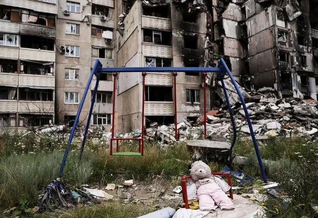 A teddy bear is seen next to a swing, next to buildings destroyed by military strikes, as Russia's invasion of Ukraine continues, in Saltivka, one of the most damaged residential areas of Kharkiv, Ukraine on July 17, 2022. (Photo by Nacho Doce/Reuters)