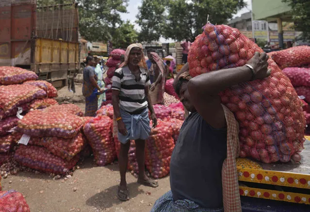 A worker places a sack of onions onto a weighing scale at a wholesale market in Hyderabad, India, Wednesday, July 20, 2022. (Photo by Mahesh Kumar A./AP Photo)